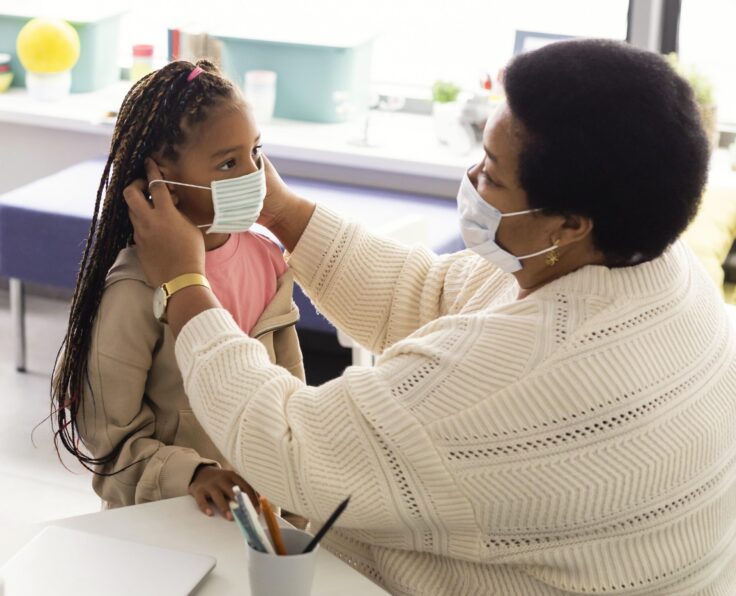 teacher-helping-student-put-medical-mask